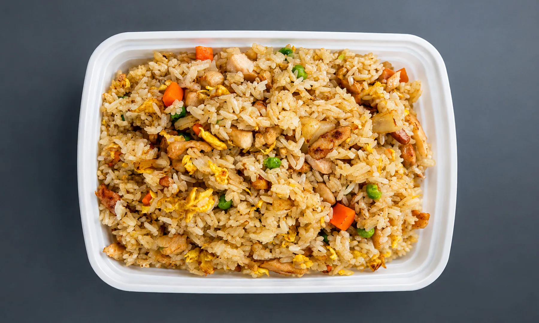 Chicken fried rice with egg, peas, and carrots in a takeout container